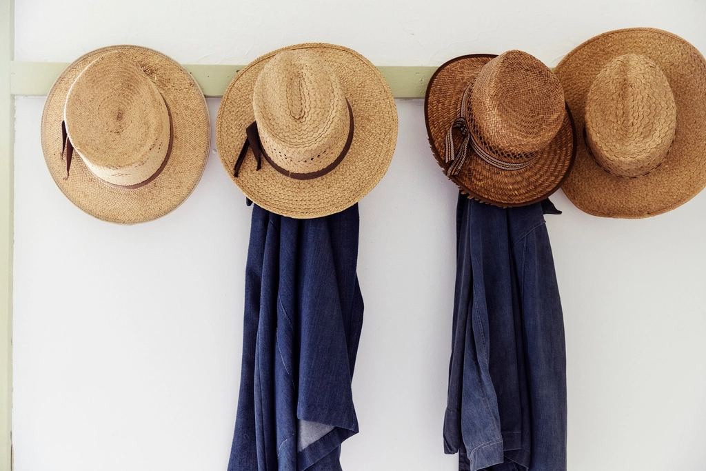 Straw hats hanging on an Amish farmhouse wall